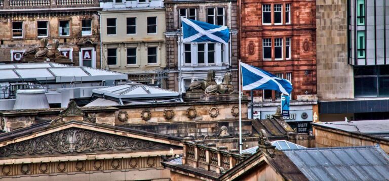 Scottish saltire flags flying above historic Glasgow rooftops